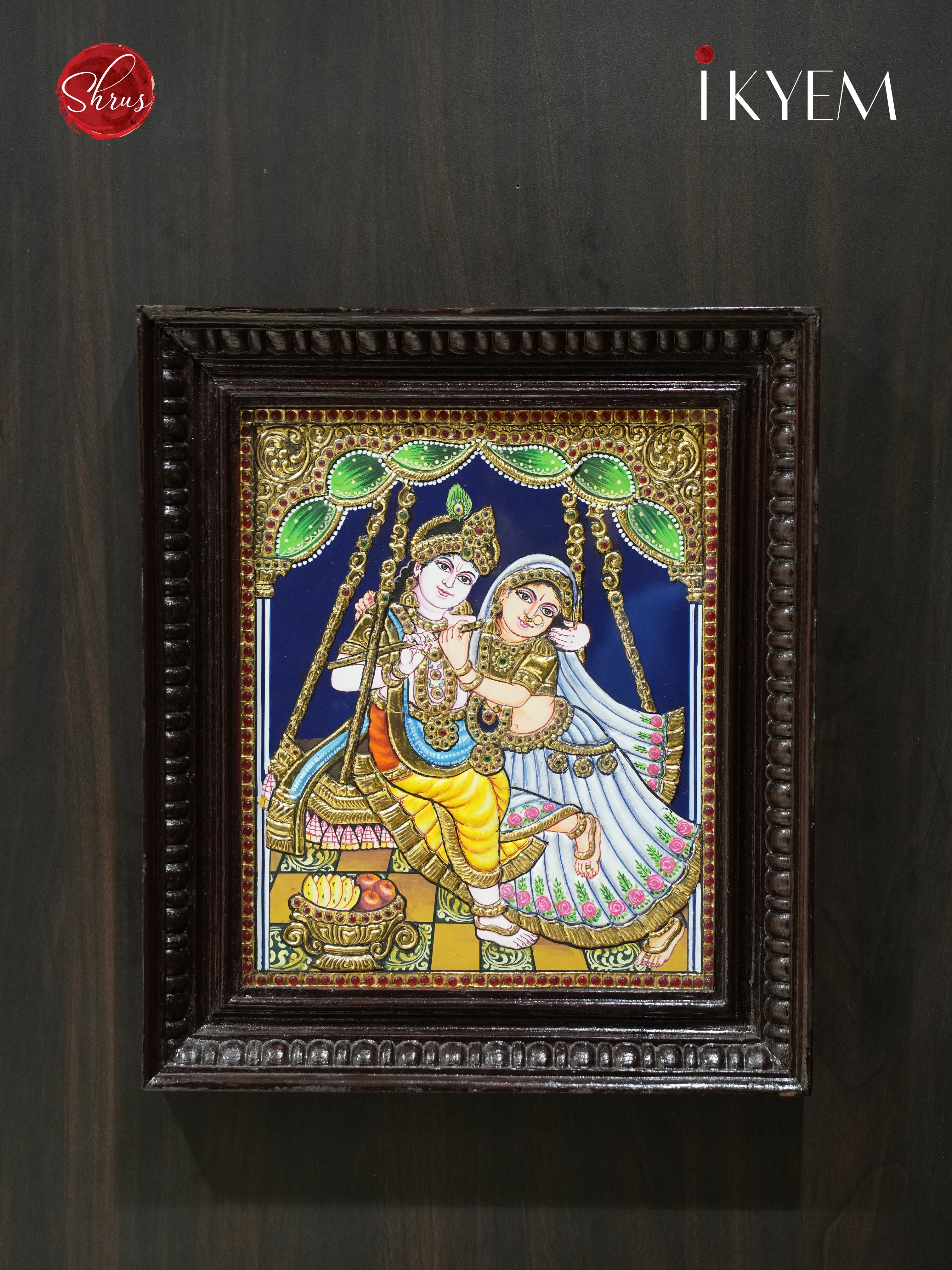 Radha Krishna on Unjal - Tanjore Painting embelished with Pure Gold Foil, Stones and Mani Frame